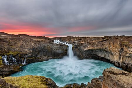 Aldeyjarfoss waterfall in Iceland at sunrise with golden clouds in the sky. Amazing landscape in beautiful tourist attraction. Wonder of nature with glacier water.の写真素材