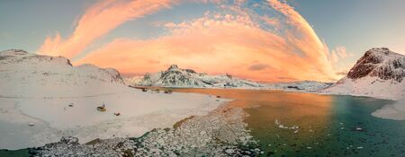 Aerial drone panorama photo. Beautiful sunset over the mountains and sea of the Lofoten Islands. Reine, Norway. Winter landscape with amazing colors.の写真素材