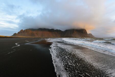 Magical landscape of Vestrahorn Mountains and Black sand dunes in Iceland at sunrise.  Panoramic...