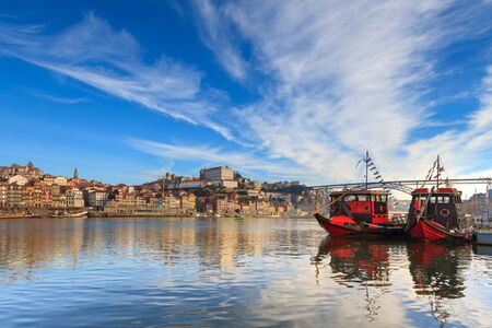 Traditional boats of the river Douro in Porto, Portugal. Oporto is an amazing tourist attraction and vacation destination in europe. Majestic travel spot. Beautiful bridge crossing Douro River.の写真素材