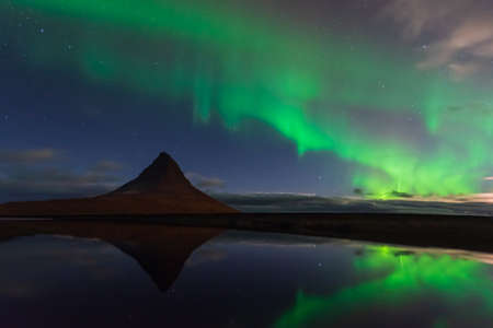 Northern lights in Iceland. Landscape full of kp5 Aurora Borealis. Amazing nightscape at Kirkjufell, scenic travel destination. Green sky full of stars.の写真素材