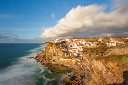 Picturesque village Azenhas do Mar. Holiday white houses on the edge of a cliff with a beach and swimming pool below. Landmark near Lisbon, Portugal, Europe. Landscape at sunset.の写真素材