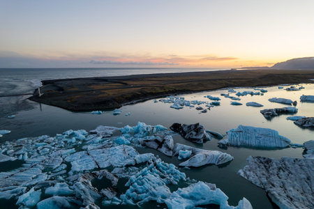 Breathtaking aerial view of Jokulsarlon Glacier Lagoon at sunset, icebergs floating in the serene...