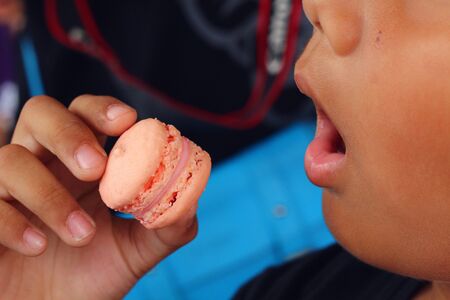 A Boy eating colour French macaroonの写真素材