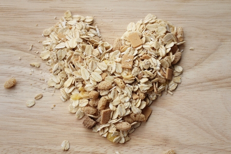 Heap of oat flakes in a shape of heart on dark wooden background, Vintage Style