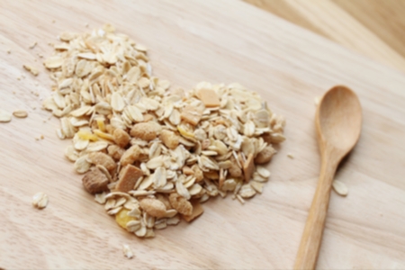 Heap of oat flakes in a shape of heart on dark wooden background