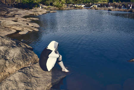 A girl sit next to river in a forest in place named Athirapally, located in Kerala state, Indiaの写真素材