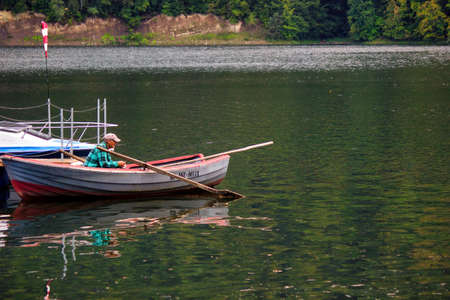 Roznow, Poland - September 04, 2014: A man fishing on a parked boat in Roznowskie lakeのeditorial素材