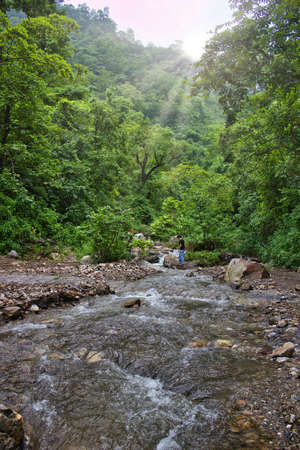 A man crossing flowing river in a forest hill