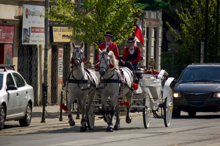 Krakow, Poland - May 03, 2015: Moving Horse cart or carriage ride on a road drive by two ladies in traditional clothingのeditorial素材