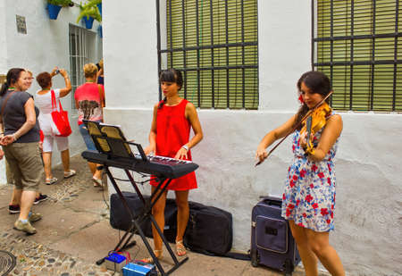 Cordoba, Spain - September 02, 2015: two young girls playing piano and violin as Street performer musician in city center main square, This is one of the main touristic attractionのeditorial素材