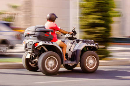 Malaga, Spain - September 04, 2015: Side view of a man wearing helmet and riding quadro four wheel scooter aka quooder in costa del solのeditorial素材