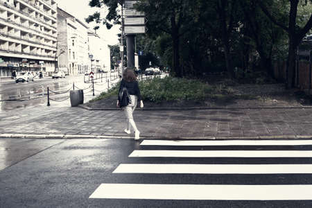 Krakow, Poland - July 18, 2020: A wide angle shot of zebra patterns on a street of Europe and a female crossing the roadのeditorial素材