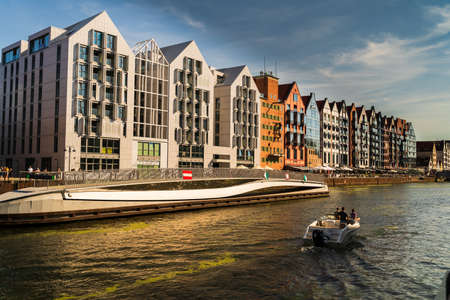 Gdansk, North Poland - August 13, 2020: People riding motor boat in summer in motlawa river adjacent to polish architecture next to baltic sea during covid 19 pandemicのeditorial素材