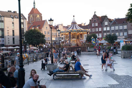 Gdansk, North Poland - August 13, 2020: People doing leisure at city center opposite Carousel horses...
