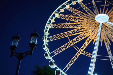 Closeup view of european style street lamp and illuminated ferries wheel behind it during night time located in old town over motlawa riverの写真素材
