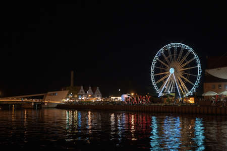 Gdansk, North Poland - August 13, 2020: Night photography of cityscape consisting old town commercial market and illuminated ferries wheel over motlawa riverのeditorial素材