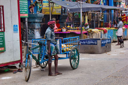 Madurai, India - November 02, 2018: A tricycle laborer standing in front of hindu temple named...