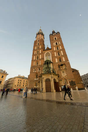 Krakow, Poland - February 22, 2021: Vertical shot of a St. Mary's Basilica catholic church of Main Market Square in Krakow, other historic buildings, commercial properties and people taking a walkのeditorial素材
