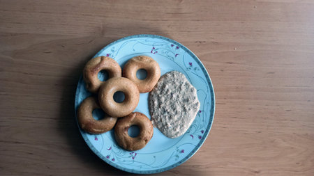 Five baked donut shaped Medhu Vada, Chili Pakora with Coconut Chutney.Delicious south Indian cuisine on a white plate against wooden background.の写真素材
