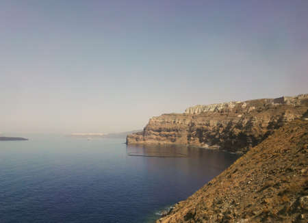 Santorini, Greece. Red volcanic island hills or mountains by the Beach, one of the most beautiful and famous beaches of Thira island, Aegean Sea, Cyclades.の写真素材