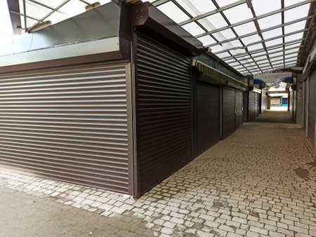 Alleyway of closed shutter of shops in the market during winter. Shutdown or lockdown out of...