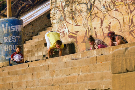Varanasi, India - November 01, 2016: Bunch of foreigner men in hipster style doing yoga in the Morning with a trainer against wall with graffiti in the city of Banaras situated in Uttar Pradeshのeditorial素材