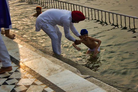 Amritsar, India - November 06, 2016: Sikh pilgrim. A Sikh father and child take a dip in the holy pool. The Harmandar Sahib , Golden Temple, in the state of Punjabのeditorial素材
