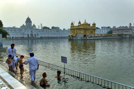 AMRITSAR, INDIA - November 06, 2016: Sikh devotees bathing or taking a dip in a pool in the Golden...