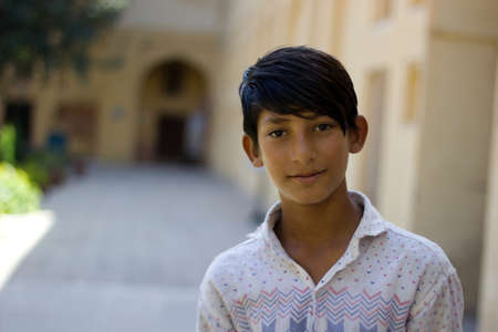 Pushkar, India - November 10, 2016: A portrait of a young Indian boy in the street of Rajasthan looking at the camera and smiling while working as a guide in one of the tourist attractionのeditorial素材