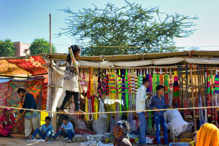 Pushkar, India - November 10, 2016: A little gypsy Indian girl doing show of walking bare foot on a rope performing acrobatic balancing act while holding bamboo stick in her hand during pushkar fairのeditorial素材