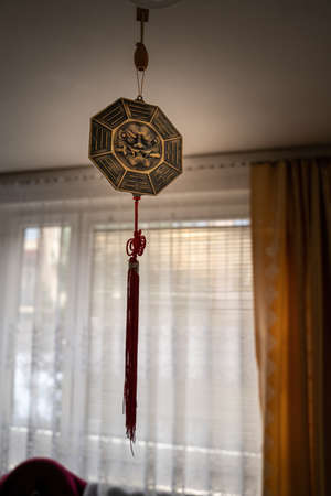 Octagon Bagua Mirror Feng Shui hanging from a roof inside a room against curtains- powerful cure to protect against negative energy and create good fortune and harmony.の写真素材