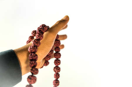 Image of Prayer beads in hand. Male hand holding rosary, praying to god on white background, religious spirituality. Man holding rosary beads and meditating. Religious conceptの写真素材