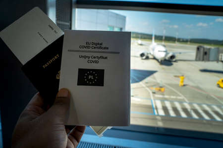 COVID-19 coronavirus pandemic and travel concept, COVID vaccination passport along with boarding pass against out of focus flight at airport. New normal way of traveling after covid pandemicの写真素材