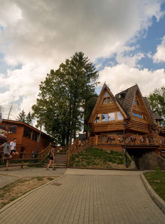 Zakopane, Poland - August 13, 2021: A shaped house or restaurant on Gubalowka next to a tree against dramatic cloudsのeditorial素材