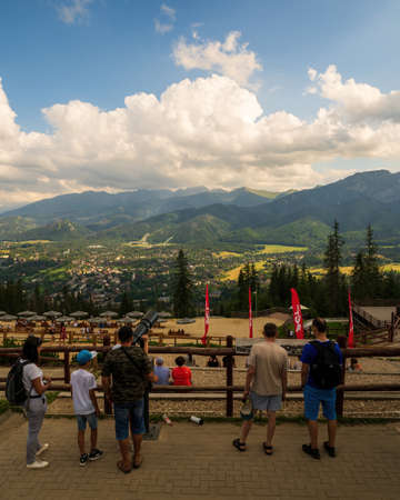 Zakopane, Poland - August 13, 2021: Tourist looking through a telescope towards gubalowka mountain landscape in Zakopane against giewont mountains in the backgroundのeditorial素材