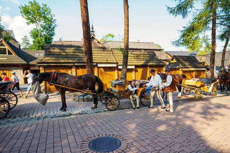 Zakopane, Poland - August 14, 2021: Bunch of Men in polish traditional clothing standing next to a horse carriage or cart in Krupowki street, the main city promenadeのeditorial素材