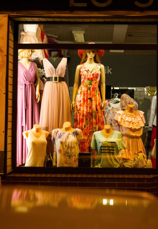 Bunch of headless mannequins show spring clothes collection. Standing dummies in store. Orange...