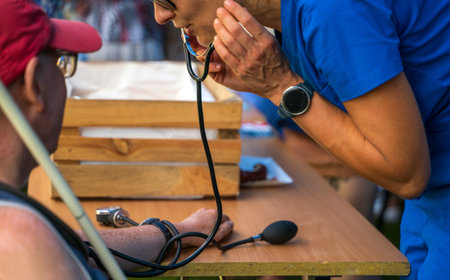 Doctor using sphygmomanometer with stethoscope checking blood pressure to a patient in the hospital.