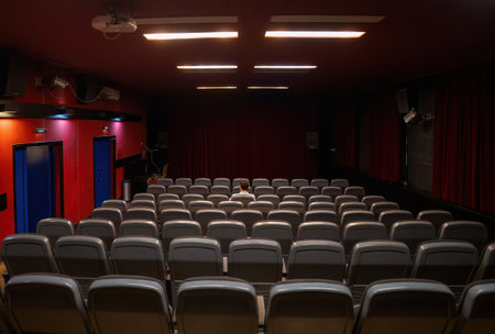 Interior of cinema hall with only one man sitting in the center, closed curtainsの写真素材