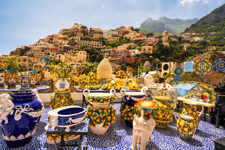 Positano, Italy - June 29, 2024: A view of colorful vase decorative items against beautiful landscape of houses built on a hillの写真素材