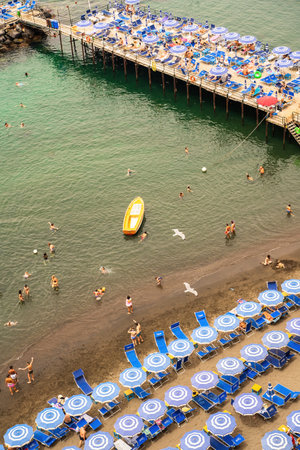 Sorrento, Italy - 07.24.2019: People relaxing on the beach on the pier and swimming in the sea on inflatable air beds and boats floatingの写真素材