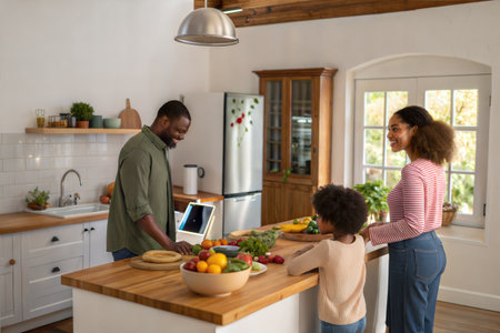 Happy african american family preparing food together in the kitchen at homeの素材