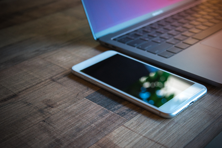 Computer Laptop and white mobile phone with tablet on wooden table background, blank screen electronic device with copy spaceの写真素材