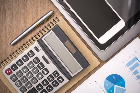 business documents on office table with smart phone and digital tablet and graph financial with social network diagram and computer laptop on wood deskの写真素材