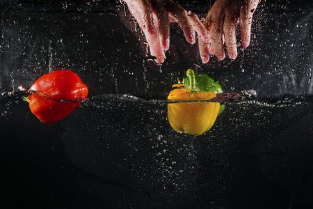 hand on top of several coloured paprika falling into water splash with many bubbleの写真素材