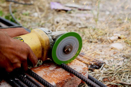 man is cutting iron road with help of iron cutter machine with golden sparkling come out of itの写真素材