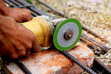 man is cutting iron road with help of iron cutter machine with golden sparkling come out of itの写真素材