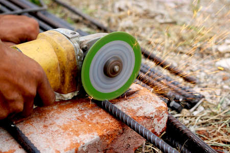 man is cutting iron road with help of iron cutter machine with golden sparkling come out of itの写真素材