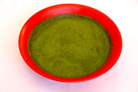 Green chutney(sauce) in red bowl with white backgroundの写真素材